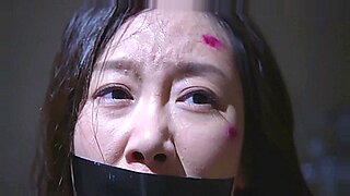 Scena BDSM z udziałem azjatyckiej piękności, która zakleja taśmę ustami i dusi się na dużym kutasie.